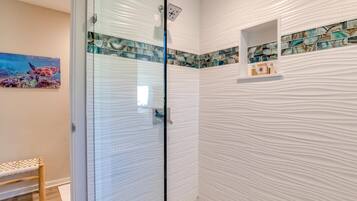 A bathroom with a glass door, a bench, and a mosaic tile backsplash.