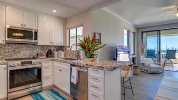 Start your mornings barefoot on cool tile, brewing coffee in this coastal kitchen while sunlight filters through the palms outside