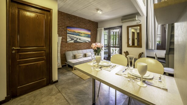 A dining area with a table set for two, a sofa, and a painting on the wall. - 32-rustico Natural.2951 José (Ciudad Autónoma de Buenos Aires, Recoleta)