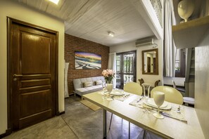 A dining area with a table set for two, a sofa, and a painting on the wall. - 32-rustico Natural.2951 José (Ciudad Autónoma de Buenos Aires, Recoleta)