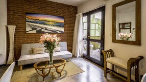 A living room with a brick wall, a sofa, a coffee table, a bench, and a large window with curtains. - 32-rustico Natural.2951 José (Ciudad Autónoma de Buenos Aires, Recoleta)