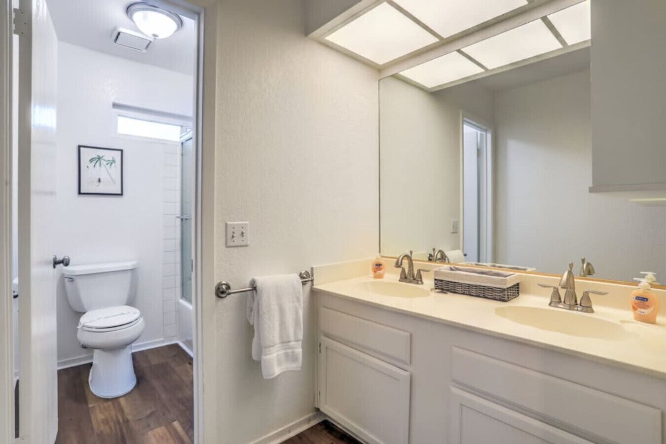 A bathroom with a toilet, a sink with a mirror, and a towel rack.