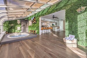 A modern interior with a hot tub, wooden flooring, a kitchen area, and a green wall.