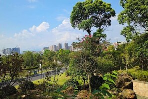 A park with trees, a pathway, and a view of buildings in the distance. - Donghu Hotel (Yichun)