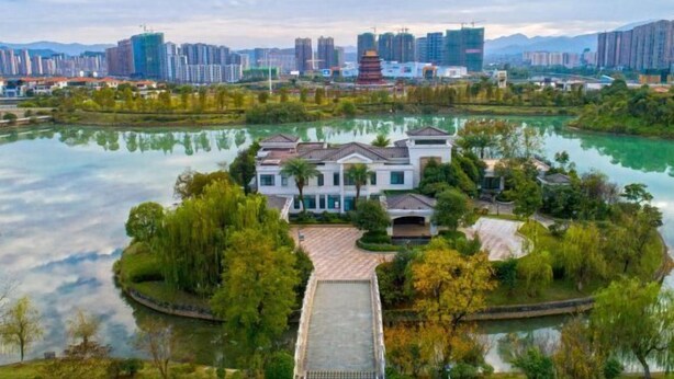 A lakeside property with a traditional-style building, surrounded by lush greenery and a calm lake. - Donghu Hotel (Yichun)