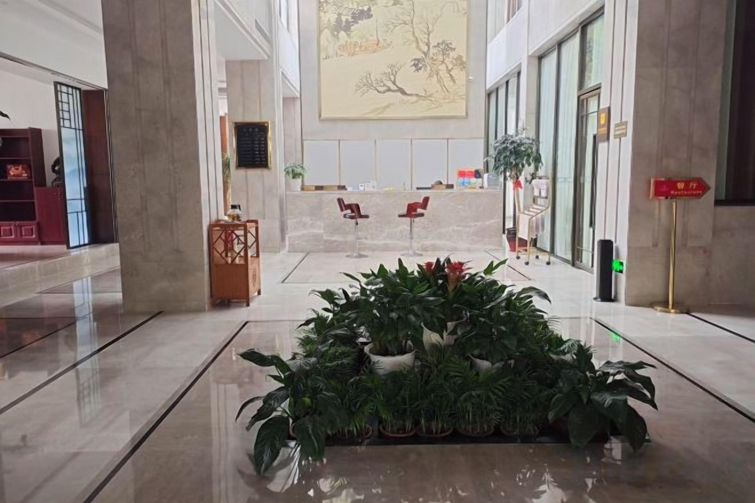 A lobby with a reception desk, seating area, and a plant arrangement.