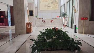 A lobby with a reception desk, seating area, and a plant arrangement.