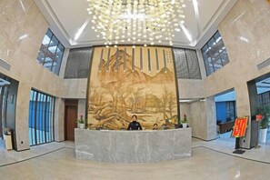 A lobby with a reception desk, a large mural, and a modern chandelier. - Donghu Hotel (Yichun)