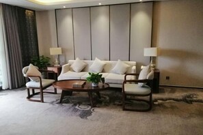 Una sala moderna con un sofá, dos sillones, una mesita de centro y lámparas.