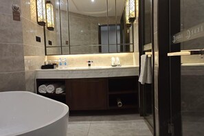 A modern bathroom with a large bathtub, a vanity with a mirror, and a shower area.