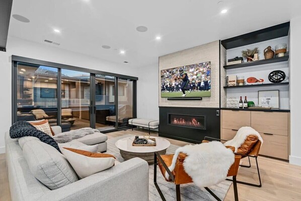 A modern living room with a fireplace, comfortable seating, and a large TV screen. - Canyons Ridge - Brand New Ski In Townhouse (Park City)