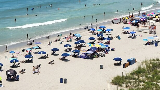 A beach with people swimming and sunbathing, umbrellas, and beach chairs. - Ashworth 1001 4-Bedroom Oceanfront Condo, "Picture Perfect" (North Myrtle Beach)