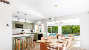 Una cocina moderna con comedor, ventanas amplias y vista a una piscina.