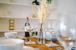 A dining table set with wine glasses, a vase with dried flowers, and a bottle of wine. - Lovely house, great location, perfect for couples! (Chester)