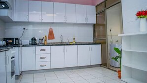 A kitchen with white cabinets, a sink, and a countertop. There is a plant on the right side. - Impeccable Family Friendly Apartment in Nairobi (Nairobi)