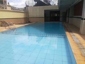A swimming pool with a tiled floor and a metal ladder.