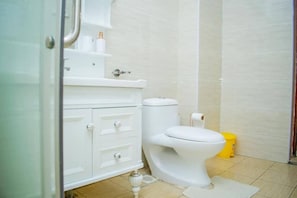 A bathroom with a toilet, a sink, and a yellow trash bin.