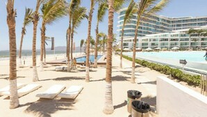 A resort with palm trees, a pool, and a modern building with balconies.