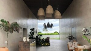 A modern reception area with a concrete reception desk, hanging pendant lights, and potted plants.