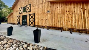 Un bâtiment en bois doté d’un toit en pente, de grandes fenêtres et d’un patio en béton aménagé avec des bancs et des poubelles.