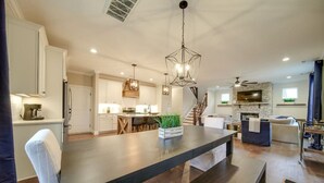 Une cuisine spacieuse dotée d’un îlot central, un coin repas avec une table en bois foncé et un salon agrémenté d’une cheminée en pierre.