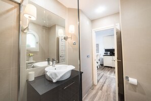 Une salle de bain moderne avec un grand miroir, un lavabo blanc et un espace douche.
