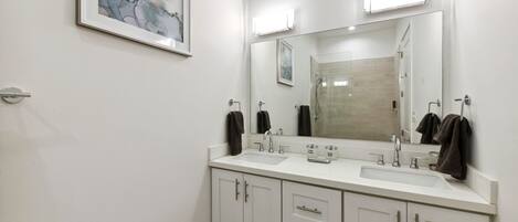 Un baño moderno con dos lavamanos, un espejo grande y un cuadro abstracto enmarcado en la pared.