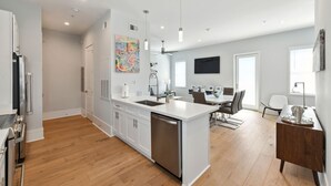 A modern kitchen with white cabinetry, a central island, and a dining area with a table and chairs.
