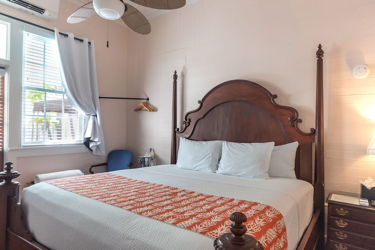 A neatly made bed with a patterned bedspread, a wooden headboard, and a bedside table with a lamp.