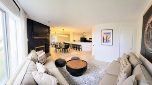A modern living room with a sofa, coffee table, and a dining area with chairs and a table. There is a kitchen area in the background with a refrigerator and a microwave. - Newly Renovated 2BR - walk to lift;  walk to Stratton Village; easy parking (Stratton)