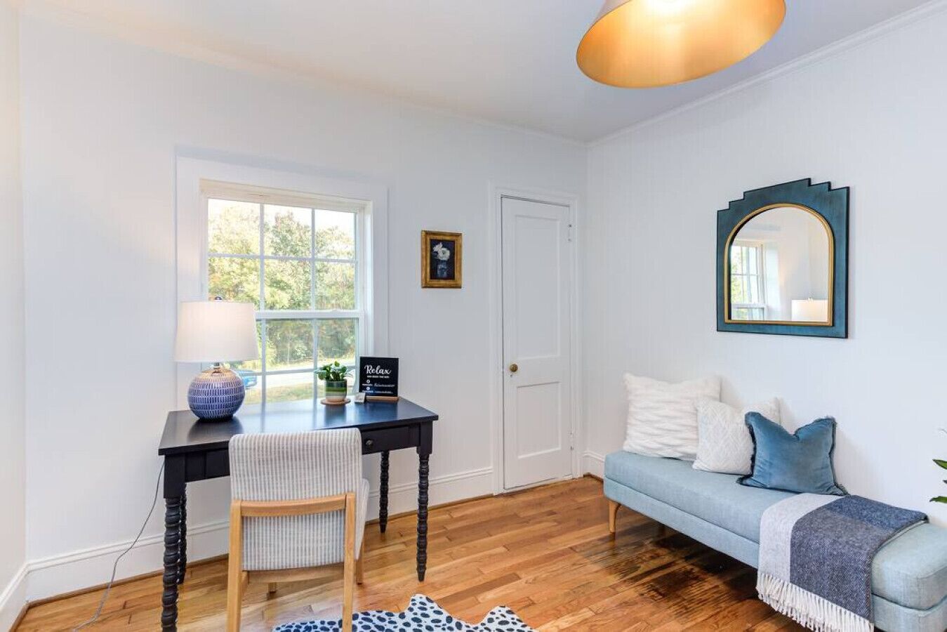 A room with a desk, chair, and a light blue sofa.