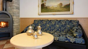 A cozy living room with a stone fireplace, a blue floral sofa, and a round table with silver tea sets. - Top Located Alpin-Residence Amadeus*** Luxury Alpine GEM for 5 Pax (Seis)