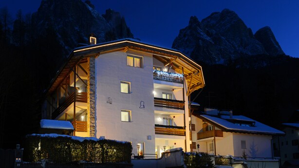A multi-story hotel with a snow-covered roof, wooden balconies, and a mountain backdrop. - Top Located Alpin-Residence Amadeus*** Luxury Alpine GEM for 5 Pax (Seis)