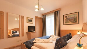 A hotel room with a large bed, a television, a painting on the wall, and a window with curtains. - Top Located Alpin-Residence Amadeus*** Luxury Alpine GEM for 5 Pax (Seis)