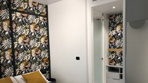 Une chambre d’hôtel moderne, équipée d’un lit, d’une armoire et d’une salle de bain visible à travers une porte ouverte.