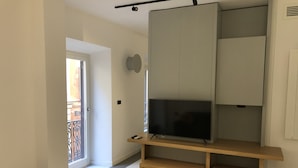 Un salon moderne avec un téléviseur à écran plat posé sur un meuble en bois, une armoire à portes coulissantes et un petit banc.