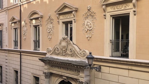 Une façade d’immeuble ornée de détails architecturaux raffinés, comprenant une entrée imposante avec une porte et une enseigne indiquant « POSTE ET TÉLÉGRAPHE ».