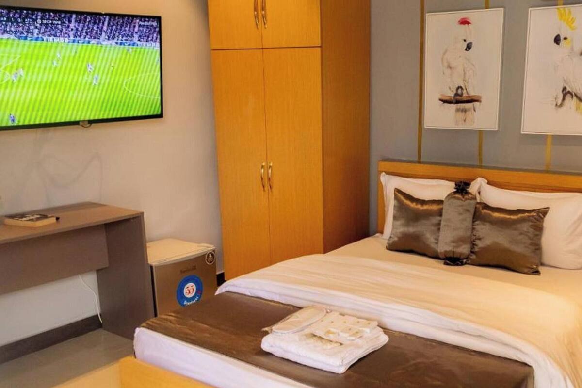 A hotel room with a bed, a desk, a television, and artwork on the wall.