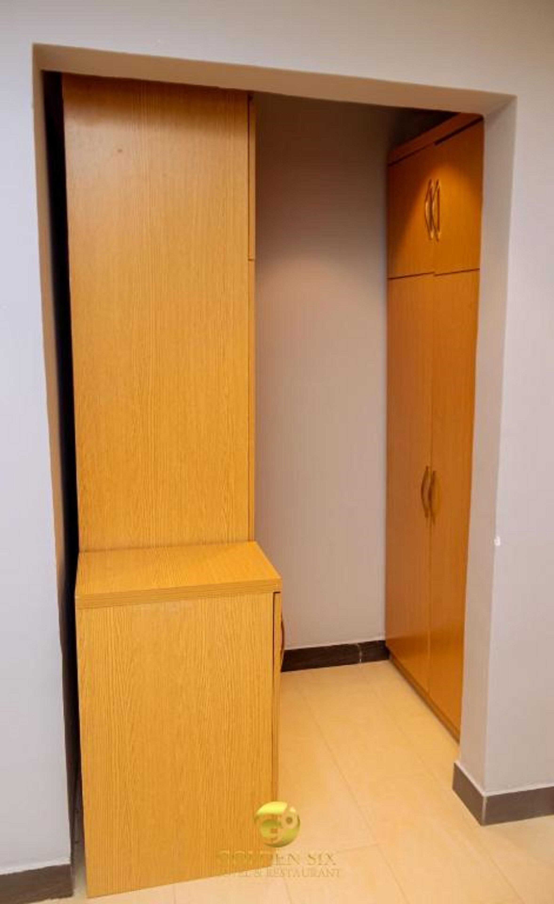 A corner room with a wooden wardrobe and a small bench.