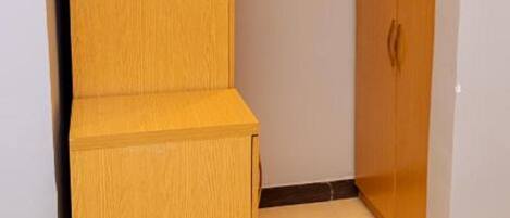 A corner room with a wooden wardrobe and a small bench.