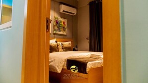 A hotel room with a bed, an air conditioner, and a painting on the wall. - Golden Six Hotel & Restaurant (Lekki)