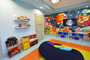 A children's playroom with a colorful mural, shelves with toys, a play table, and a bean bag chair. - Lovely Champions Gate Home with Game Room (Davenport)