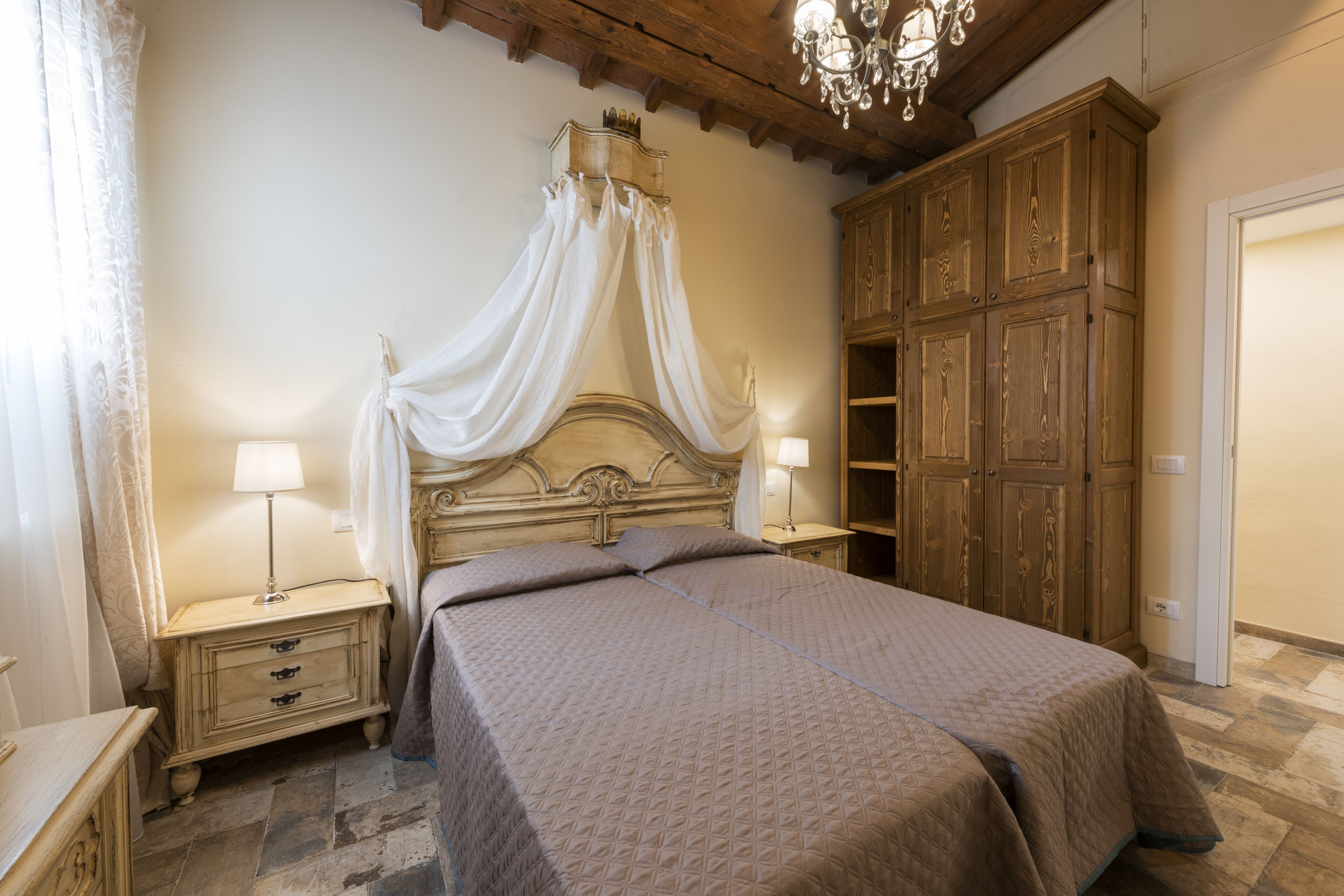 Ein Schlafzimmer mit einem Himmelbett, einem Holzschrank und zwei Nachttischen mit Lampen.