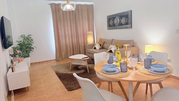 A modern living room with a dining area, a sofa set, a TV mounted on the wall, and a potted plant. - MODERN APARTMENT IN THE CENTER OF MARBELLA (Marbella)