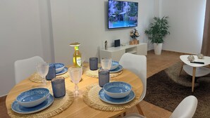 A modern dining area with a wooden table set for two, a television mounted on the wall, and a potted plant in the corner. - MODERN APARTMENT IN THE CENTER OF MARBELLA (Marbella)