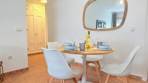 A dining area with a round table, white chairs, and a mirror on the wall. - MODERN APARTMENT IN THE CENTER OF MARBELLA (Marbella)