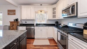 Une cuisine moderne avec des meubles blancs, des appareils en acier inoxydable et un plan de travail en granit.