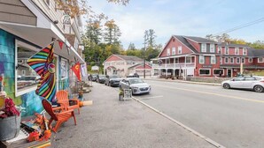 Une vue de rue avec une rangée de voitures garées, un immeuble à la façade rouge et une enseigne colorée sur la gauche.