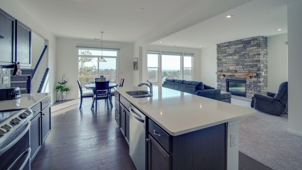 A modern kitchen with a central island, a dining area with a table and chairs, a built-in fireplace, and a view of the outdoors. - Modern Canton Home: 10 Mi to Lake Allatoona! (Canton)