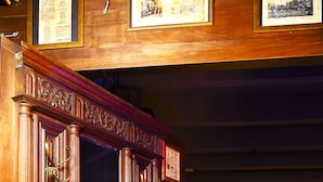 A wooden cabinet with ornate carvings and a mirror, situated in a room with patterned floor tiles and a dark ceiling. - Mala Vecindad Centro Historico (Mexico City)